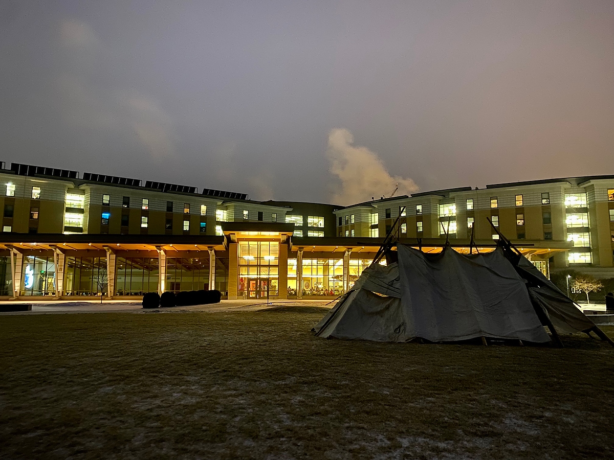 Indigenous lodge at night in front of Dejope Residence Hall