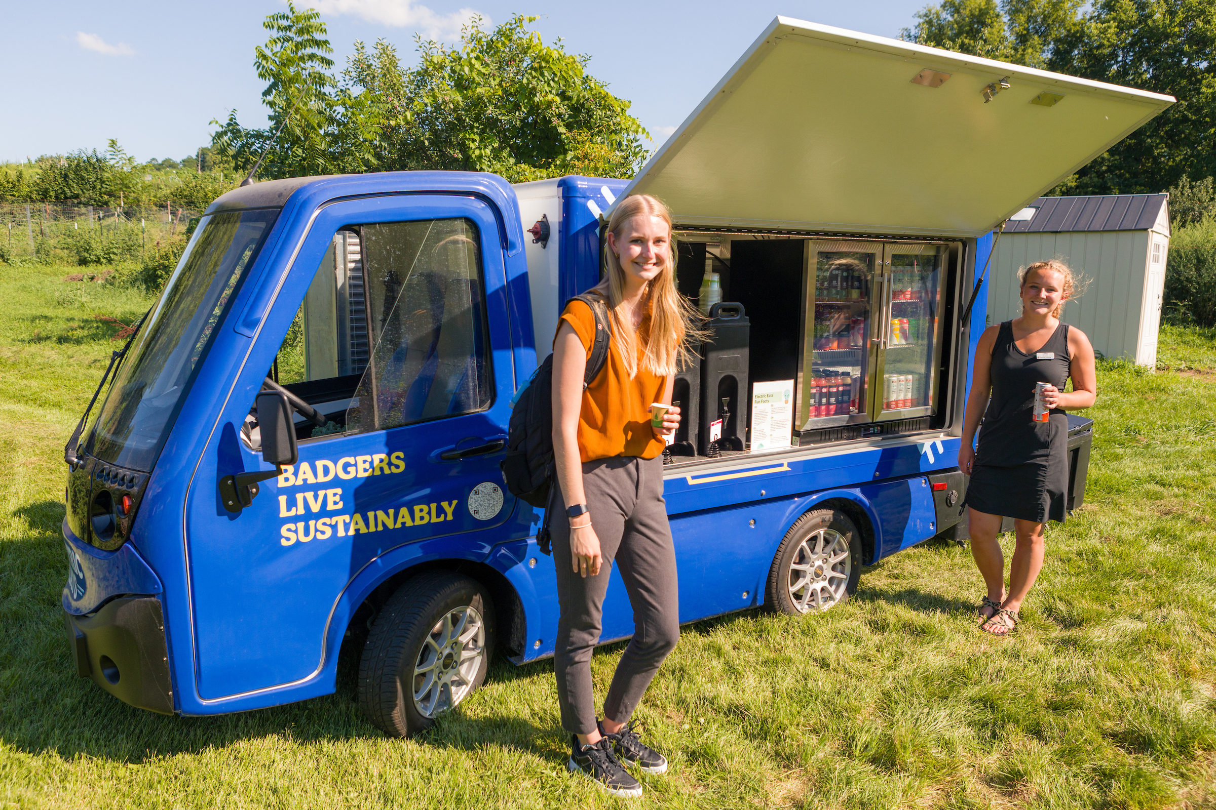 Two students stand in front of the open Electric Eats food truck at the Eagle Heights community gardens