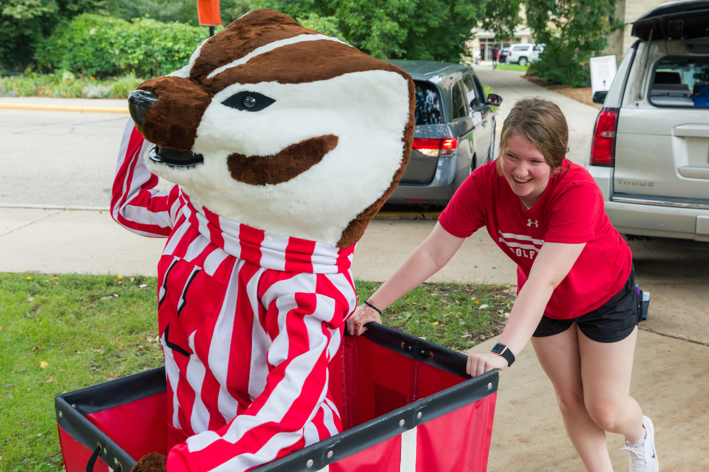 A student pushes Bucky Badger around in a red cart