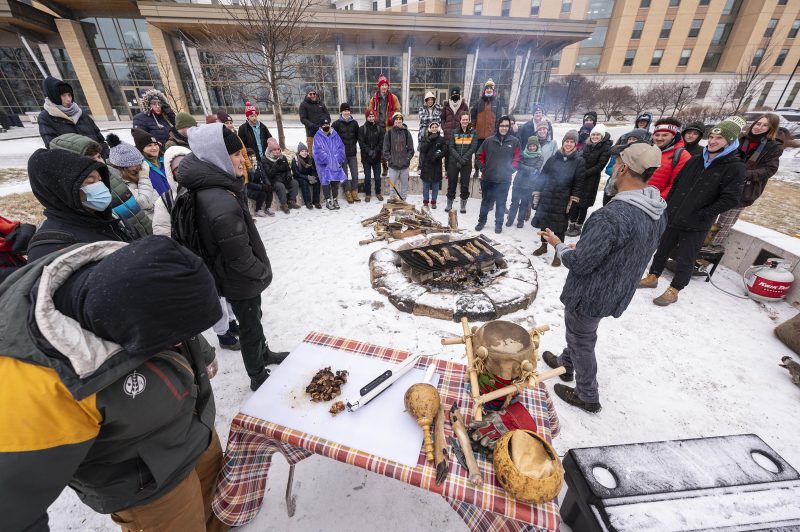 Guest lecturer Jon Greendeer speaks with students in an Indigenous Foodways: Food and Seed Sovereignty class as a group gathers around a campfire on the snow-dusted lawn of Dejope Residence Hall