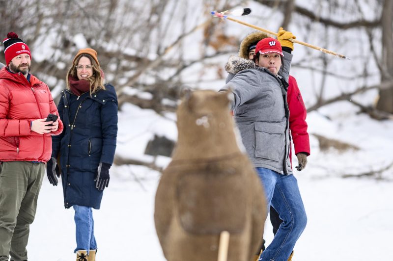 Silas Cleveland, a Ho-Chunk Nation member and UW student, prepares to throw a lance at a bear-shaped target in the Zhiimaagan Ataadiiwin game at the Ojibwe Winter Games on Lake Mendota