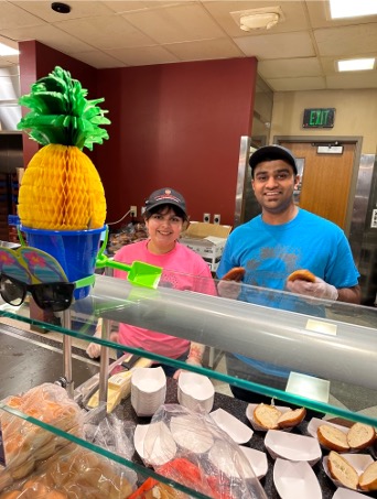Two Dining staff in brightly colored shirts pose for a photo during Bucky's Island Adventure