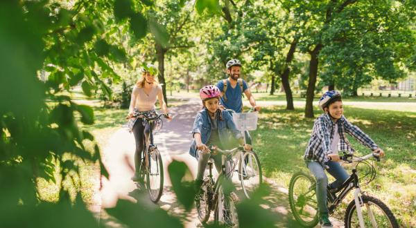 Two adults and two children riding bicycles with helmets on a bike path