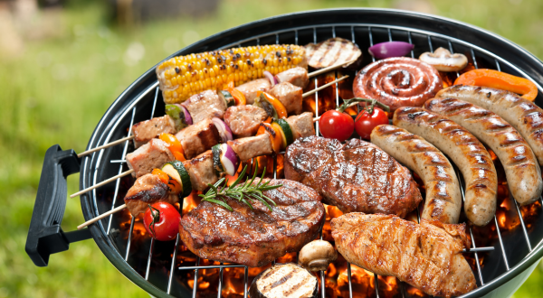 A grill full of meat, vegetables, and kabobs