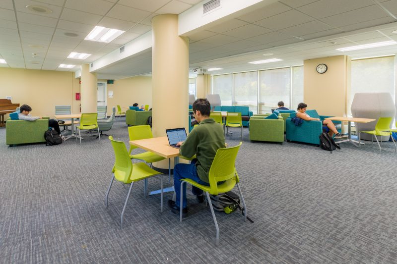 Students studying in the Chadbourne first floor lounge on bright green and blue furniture