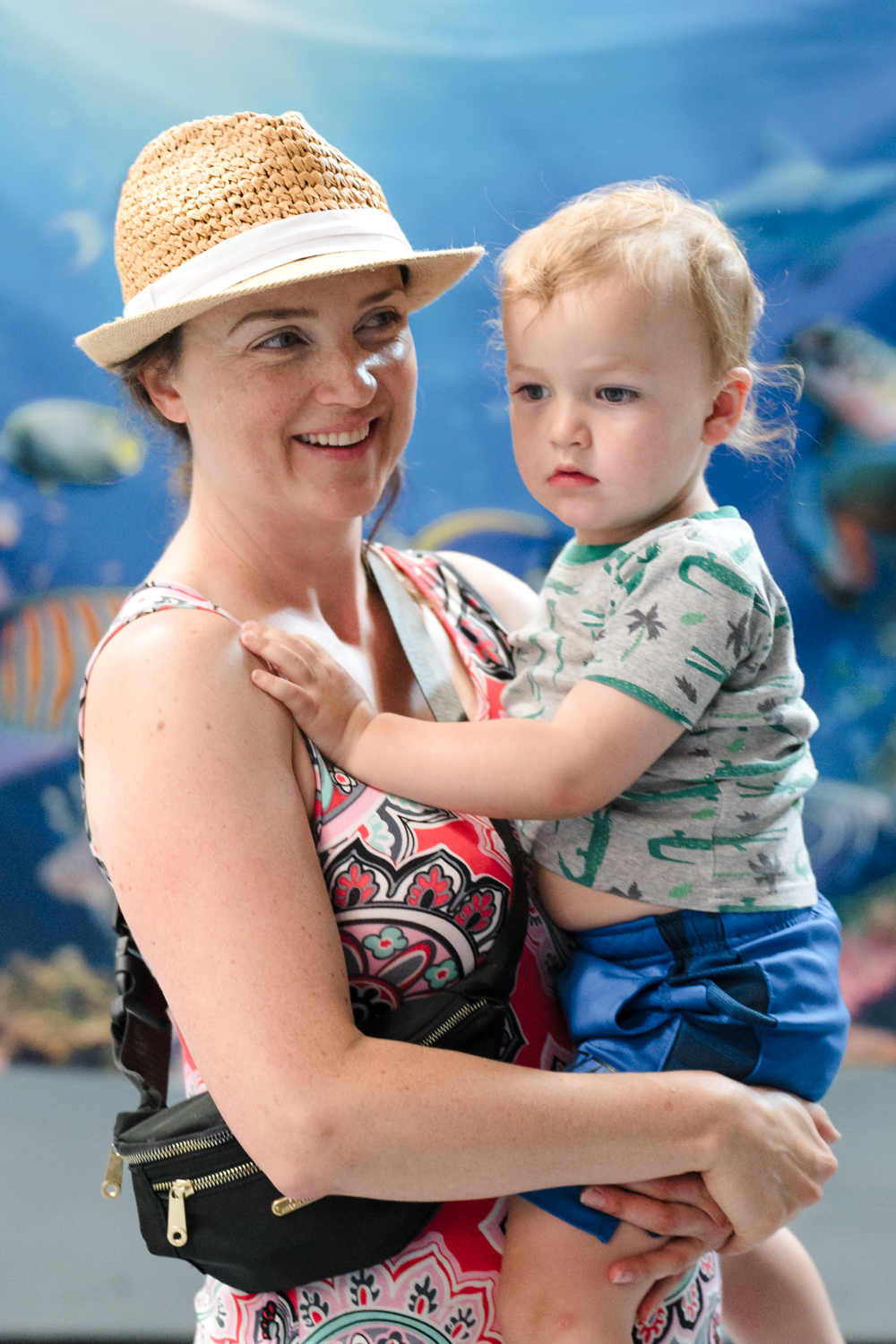 An adult holding a child in front of an ocean-themed backdrop
